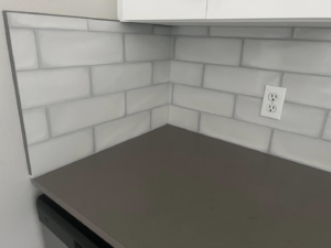 Close-up of a neatly installed subway tile backsplash and countertop corner by Fox Solutions Corp in Worcester, MA