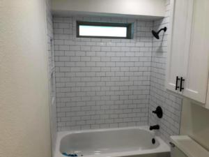 A subway tile shower and tub with modern black fixtures completed by Mason Contracting in Levittown, PA.