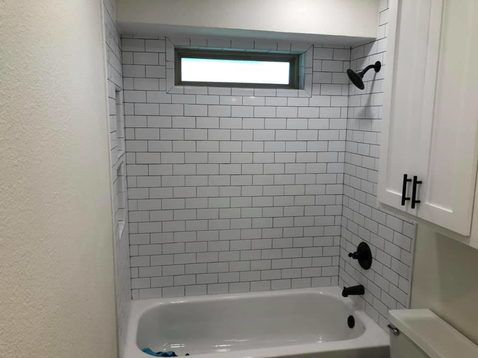 A subway tile shower and tub with modern black fixtures completed by Mason Contracting in Levittown, PA.