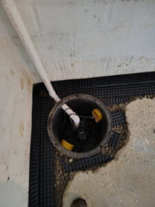 A newly installed sump pump system in a basement by ARK Basement Services - Erie, PA