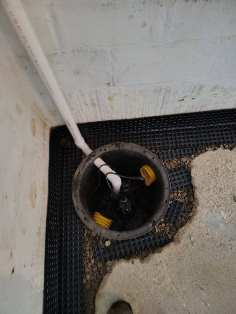 A newly installed sump pump system in a basement by ARK Basement Services - Erie, PA