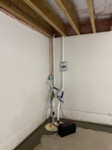 A newly installed sump pump system with battery backup in a basement by Woodford Bros., Inc. in Apulia Station, NY