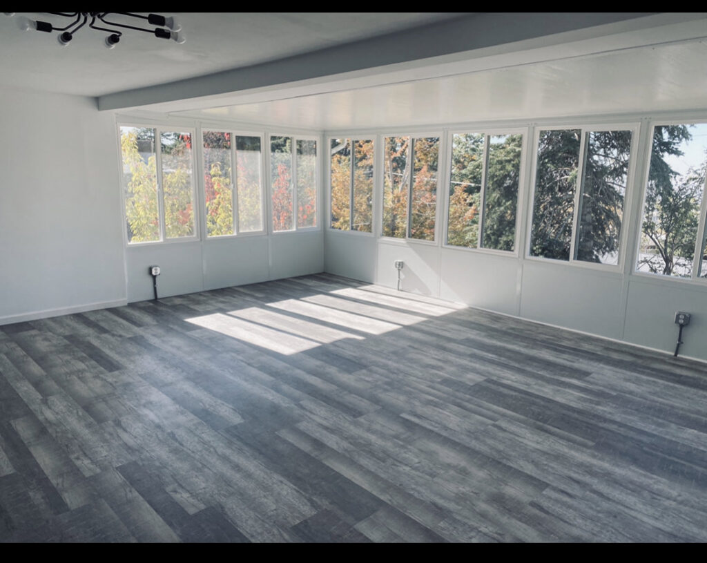 A newly finished sunroom or addition with grey plank flooring and white walls by Will.B.More Handyman & Remodel in West Jordan, UT