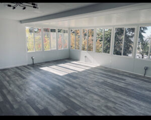 A newly finished sunroom or addition with grey plank flooring and white walls by Will.B.More Handyman & Remodel in West Jordan, UT
