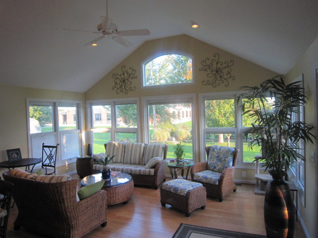 A beautifully finished sunroom addition interior with large windows and vaulted ceiling by Hibbard Home Improvement in Williamsville, NY.
