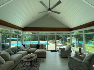 The interior of a sunroom with a ceiling fan and a view of a pool by Four Seasons of River City in Columbus, GA.