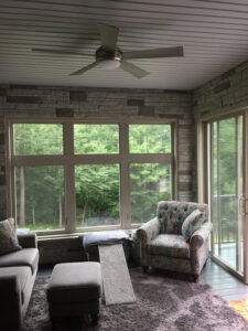 A sunroom with a stone accent wall and ceiling fan installed by S. Brown Construction Co. in Lafayette, IN