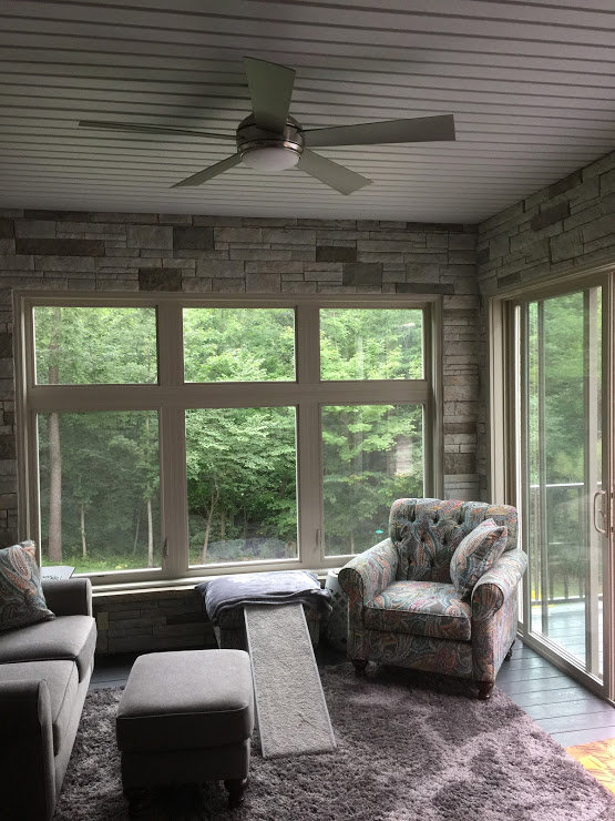 A sunroom with a stone accent wall and ceiling fan installed by S. Brown Construction Co. in Lafayette, IN