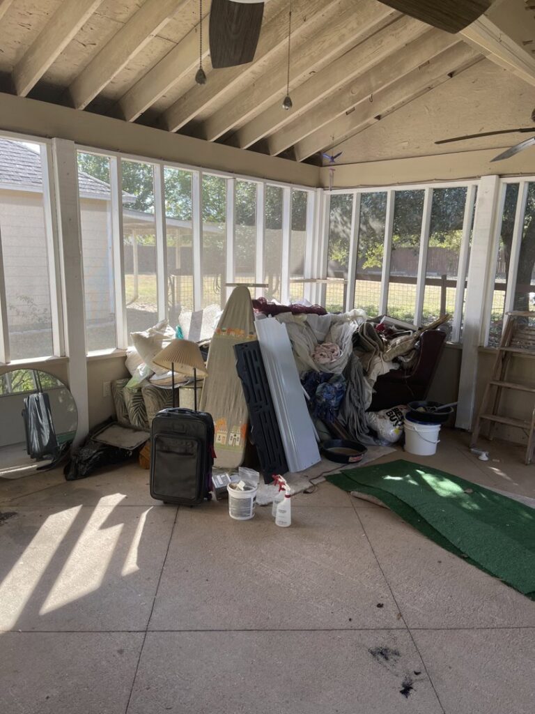 A sunroom overflowing with household clutter and old furniture, awaiting junk removal by G.I. HAUL Austin, TX.