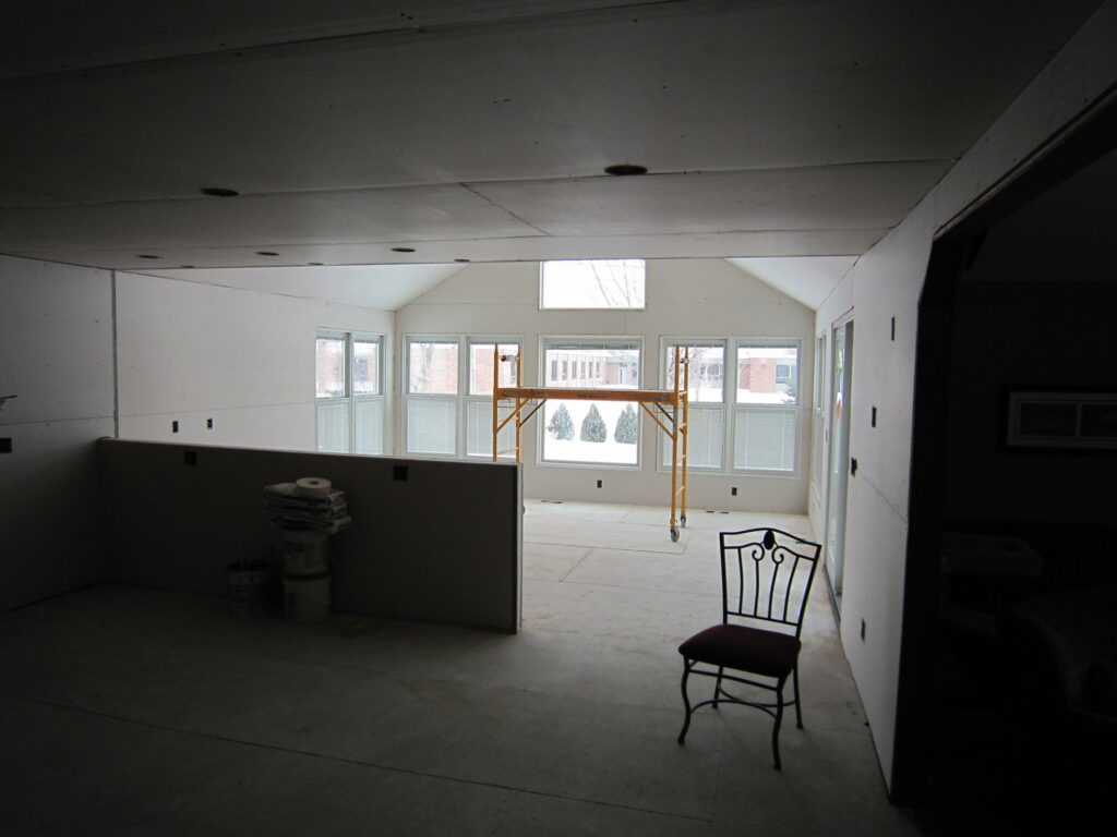A sunroom addition under construction with new drywall sheets ready for installation by Hibbard Home Improvement in Williamsville, NY.