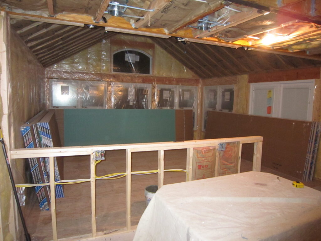 An interior view of a sunroom addition under construction, showing framing and insulation by Hibbard Home Improvement in Williamsville, NY.