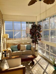 A cozy sunroom or enclosed patio with comfortable furniture and a ceiling fan, designed by NRG Industries in Tallahassee, FL.