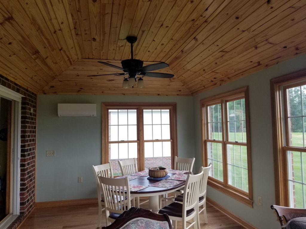 A newly renovated sunroom featuring a wooden plank ceiling, ceiling fan, and mini-split AC unit by DBB, Inc. in Harrisonburg, VA.