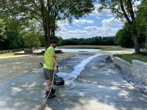 A Waterly, Co. Power Washing technician using a surface cleaner on a concrete driveway in Nashville, TN.