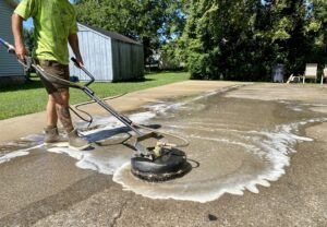 A Waterly, Co. Power Washing technician using a surface cleaner on a concrete patio in Nashville, TN.