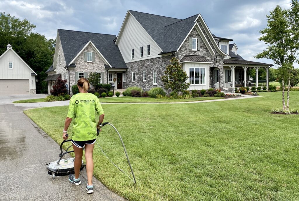 A Waterly, Co. Power Washing technician using a surface cleaner on a residential driveway in Nashville, TN.