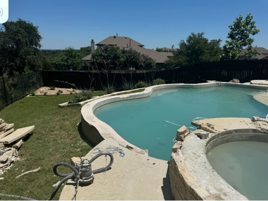 A swimming pool and hot tub area undergoing renovation by 5 Daughters Total Outdoors in Austin, TX, with broken coping visible.