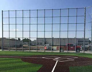 A tall chain link fence, likely a baseball backstop, installed by R & C Fence in Fort Wayne, IN.
