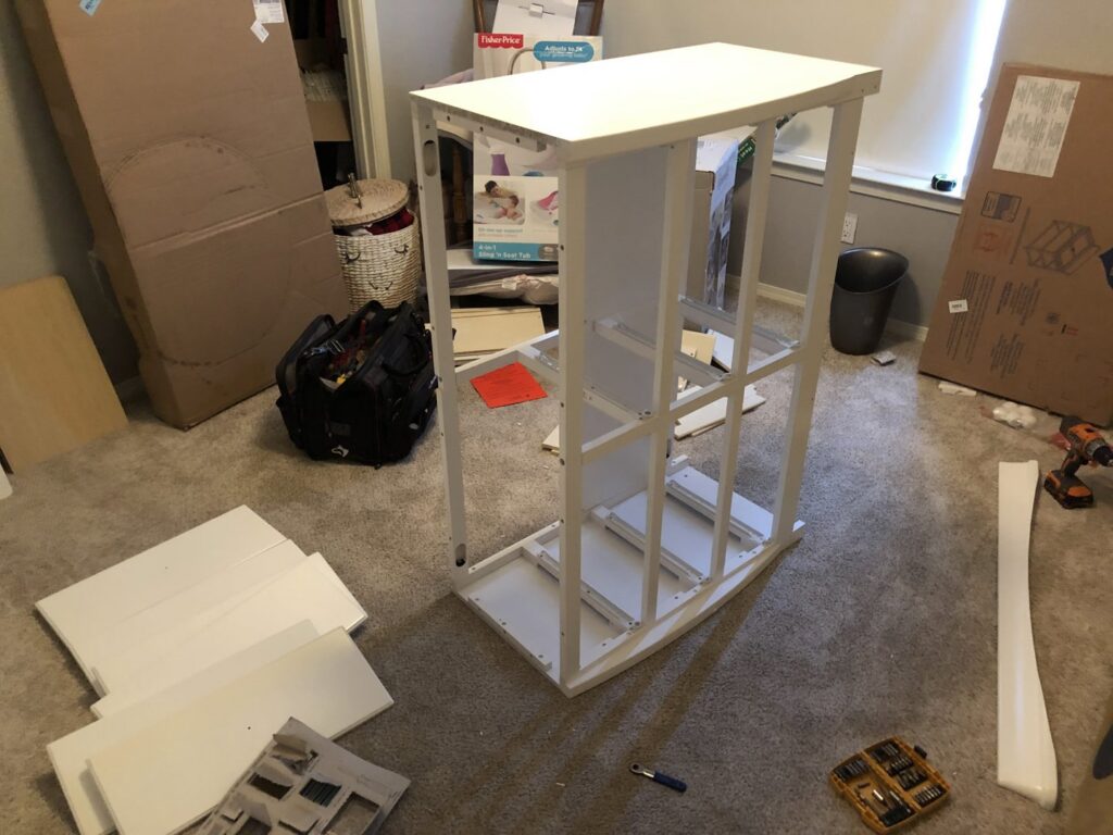 A tall white furniture piece, possibly a changing table or dresser, in the process of assembly, demonstrating services by The ABQ Handyman in Albuquerque, NM.
