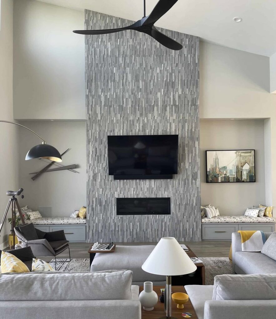 A tall tiled fireplace wall with a mounted TV in a modern living room, installed by Infinite Fire Features in Colorado Springs, CO.