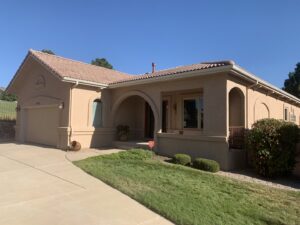 A tan stucco house with an elegant arched entryway by Greg Unseth Painting & Exteriors in Colorado Springs, CO