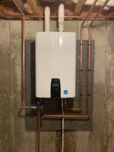 A newly installed tankless water heater with copper piping on a concrete wall by Coastal Home Improvements in Greenwood, DE.