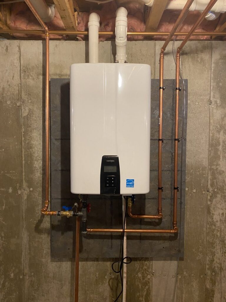 A newly installed tankless water heater with copper piping on a concrete wall by Coastal Home Improvements in Greenwood, DE.