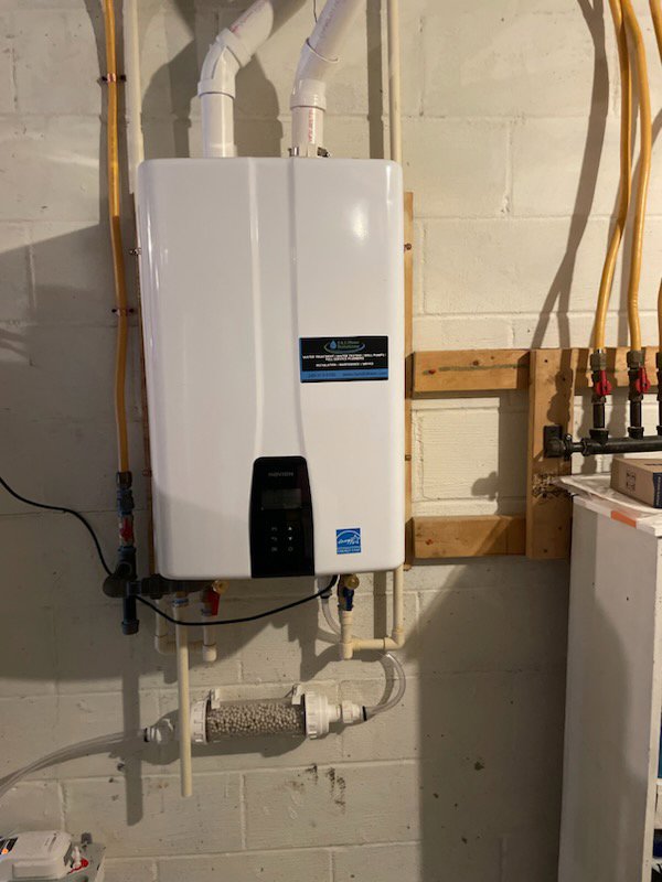 A tankless water heater installed on a wall with copper plumbing by S & L Water Solutions in Hagerstown, MD.