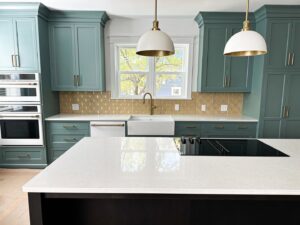 A stylish kitchen remodel with teal cabinets, a gold patterned backsplash, and white countertops by Kore Construction LLC in Cincinnati, OH.