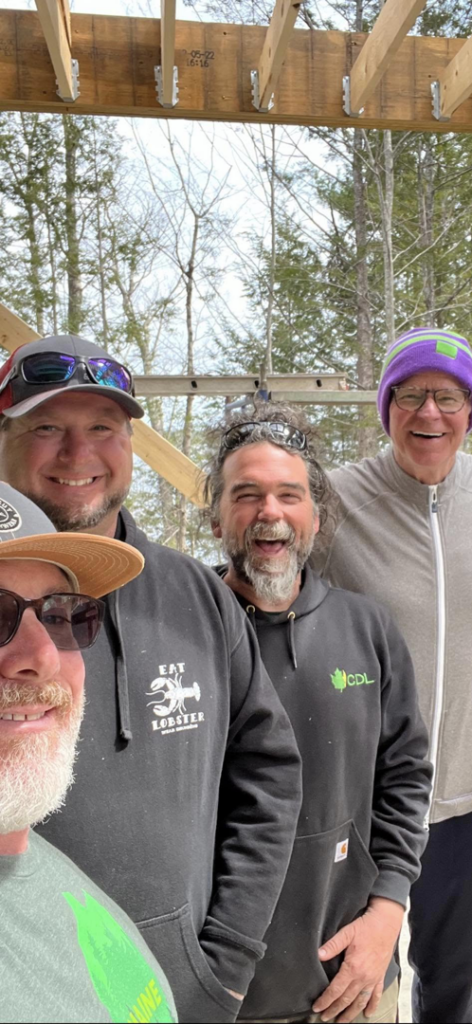 The J & J Custom Builders LLC team smiling at a construction site with exposed wooden beams in Milford, CT.