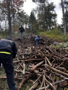 A team from Just Junk It clearing a large pile of brush and tree branches in a wooded area in Lancaster, PA.