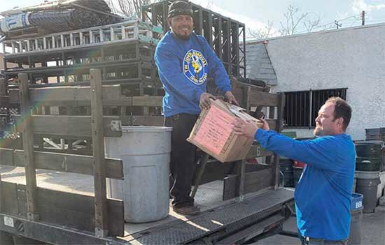 BumbleBee Junk team loading a box onto a junk removal truck with other items in Sun Valley, CA