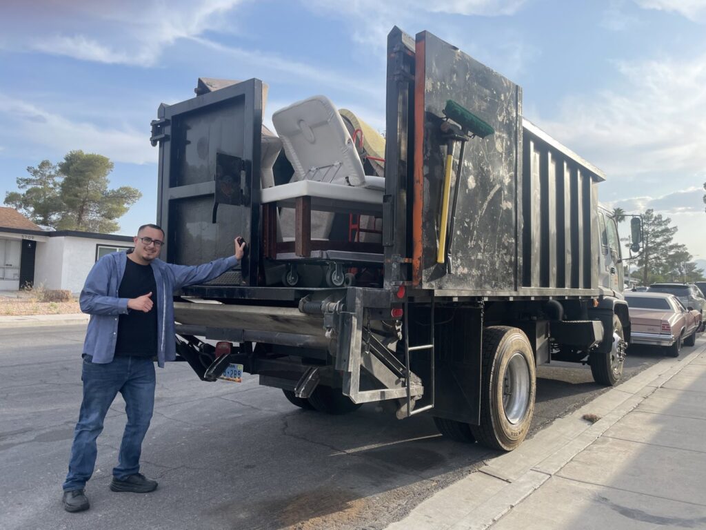 A Tidy Toss Las Vegas, NV team member giving a thumbs up next to a loaded junk removal truck.