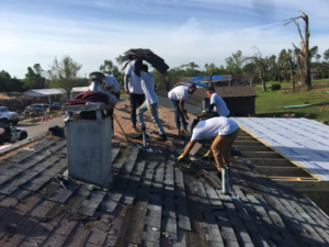 A team of workers repairing and replacing roof shingles on a house for Recover Roofing in Dayton, OH.