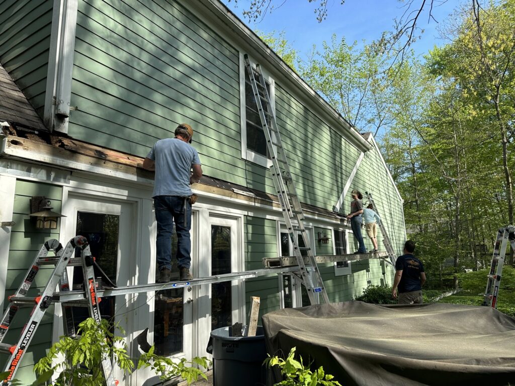 A team of workers repairing siding on a house exterior with ladders and scaffolding by Cedar Siding Repair in Centerville, OH.