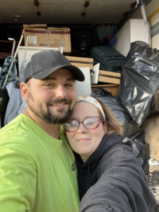 Two team members from 2 Much Junk? Junk Removal posing in front of a truck loaded with removed junk in Grand Rapids, MI.