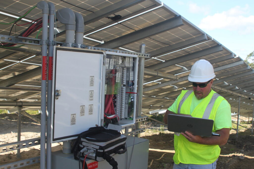 A technician checking an electrical panel at a solar installation site for Commonwealth Electrical Technologies in Worcester, MA
