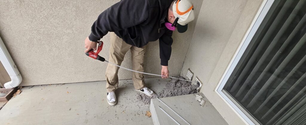 A technician from Appliance Handyman of Twin Falls, ID, cleaning a clogged dryer vent from outside a home