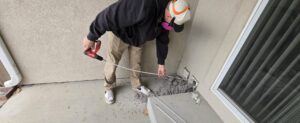 A technician from Appliance Handyman of Twin Falls, ID, cleaning a clogged dryer vent from outside a home