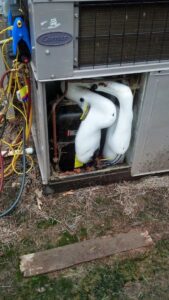 A technician from Cool Change Heating & Air diagnosing a frozen outdoor HVAC unit with gauges in Raleigh, NC.