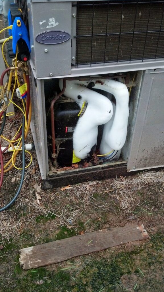 A technician from Cool Change Heating & Air diagnosing a frozen outdoor HVAC unit with gauges in Raleigh, NC.