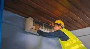 A technician in a hard hat and safety vest inspecting an indoor air conditioning unit for Advanced Mechanical Contractors, Inc. in Nashville, TN.
