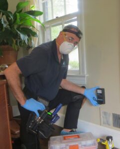 A technician using a device to inspect air quality near a vent for Indoor Environmental Systems in Cary, NC.