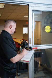 A technician inspecting an automatic sliding door and writing on a clipboard for Automatic Entrances Of Wi in Waukesha, WI.