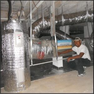 A technician inspecting a crawl space with insulated ducts and a water heater for Indoor Environmental Systems in Cary, NC.
