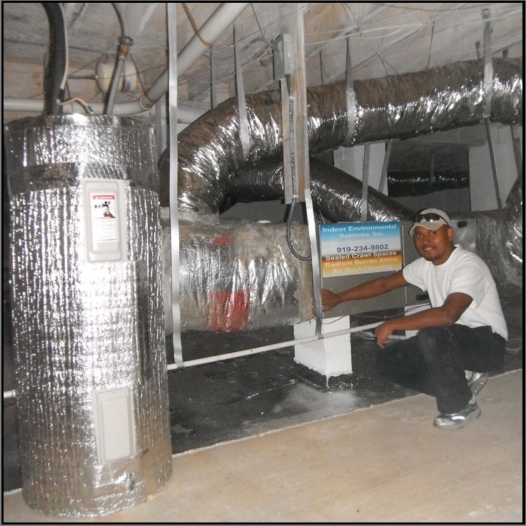 A technician inspecting a crawl space with insulated ducts and a water heater for Indoor Environmental Systems in Cary, NC.