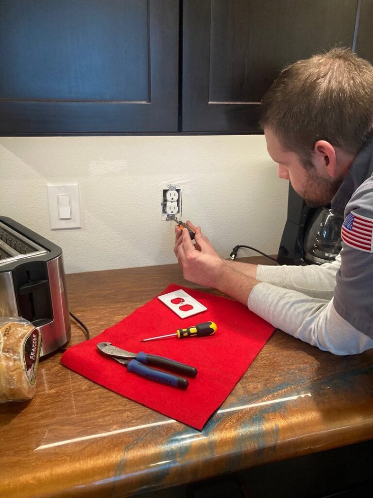Technician installing or repairing an electrical outlet in a kitchen by Epic Electric, Heating, Cooling & Plumbing in Spokane, WA