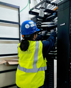 A technician managing cables in a network rack for OESCO - Oklahoma Electrical Supply Co & Infosys in Oklahoma City, OK