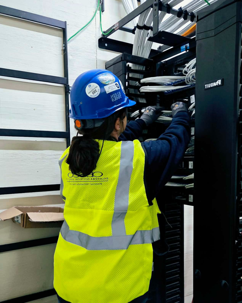 A technician managing cables in a network rack for OESCO - Oklahoma Electrical Supply Co & Infosys in Oklahoma City, OK