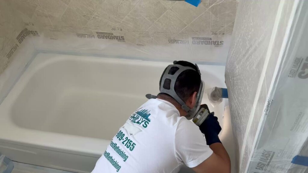 A skilled technician actively refinishing a bathtub, demonstrating work by Phillys Finest Tub & Tile Refinishing in Philadelphia, PA